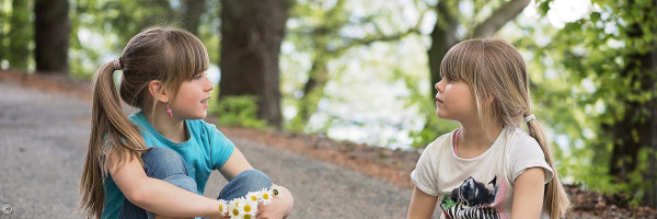 zwei Kinder, die auf dem Boden sitzen und sich unterhalten