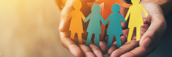 Hände, die Kinderfiguren schützend halten