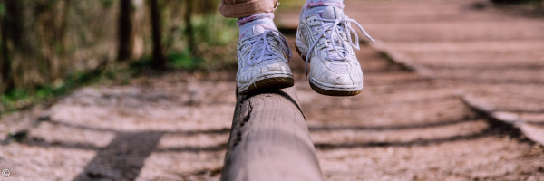 Die Füße eines Menschen, der auf einem Stamm balanciert